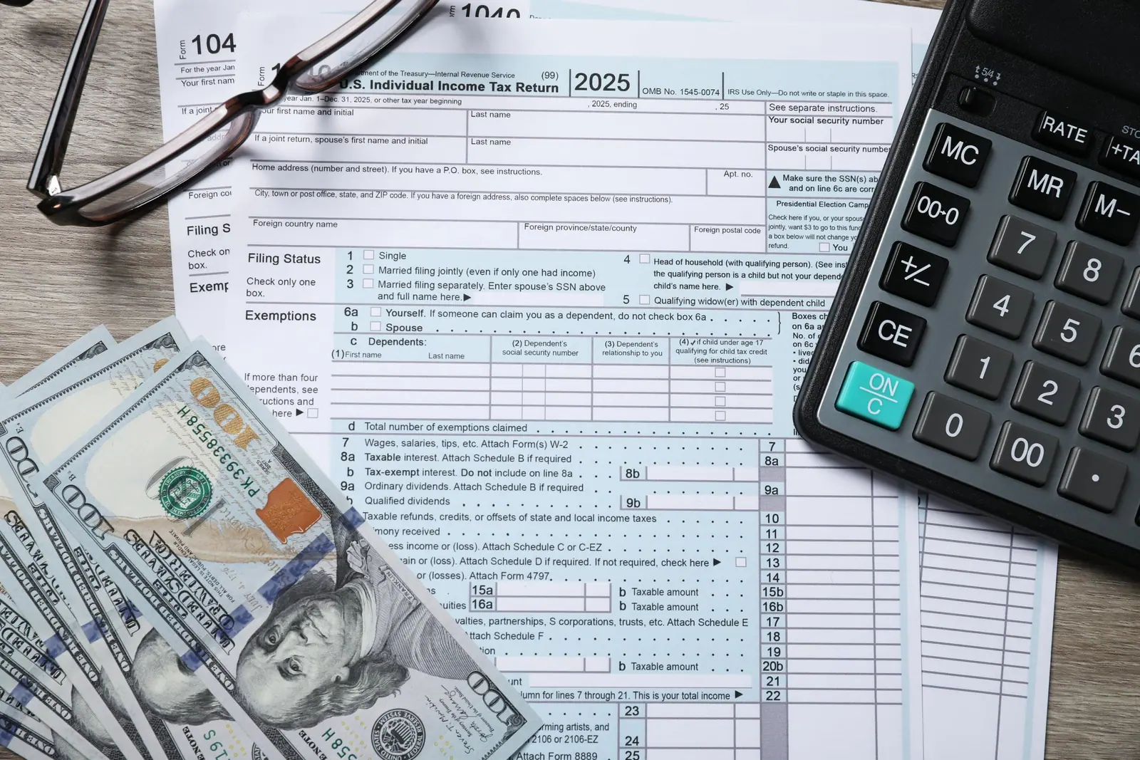 A tax return with a calculator and glasses on a desk