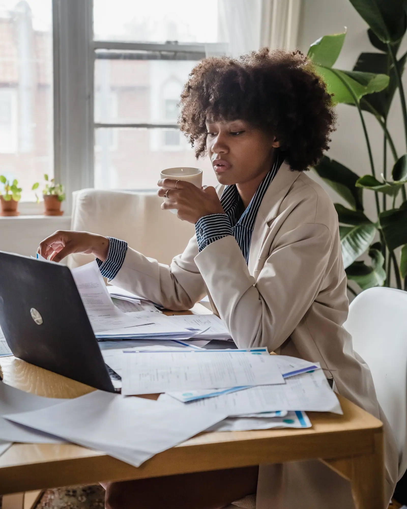Someone working at a home desk with a laptop and paperwork