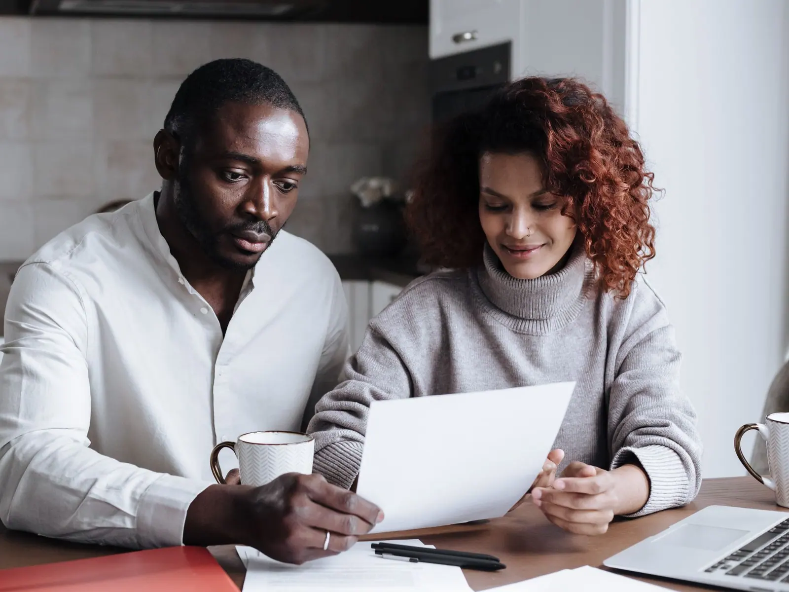 A couple reading through household financial papers at their kitchen table