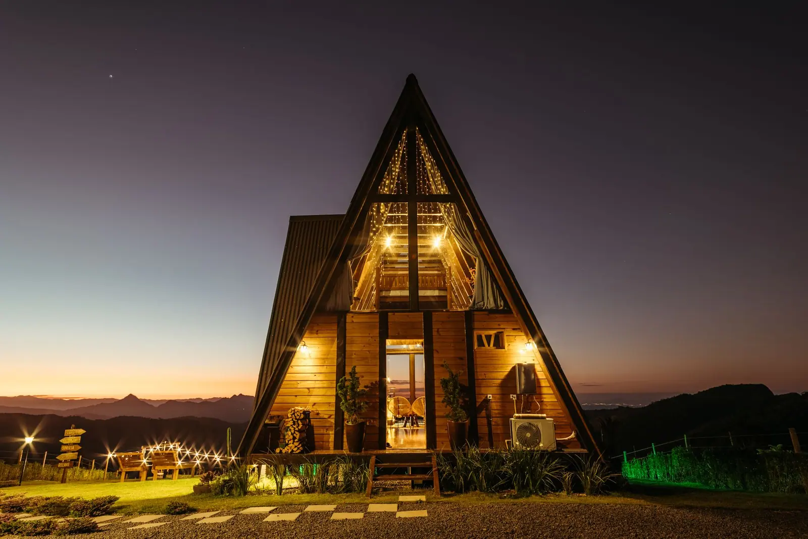 A timber rental home lit up at dusk