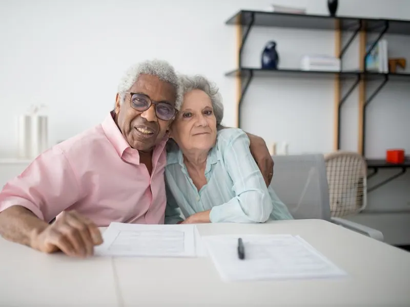 An older couple smiling together over their paperwork
