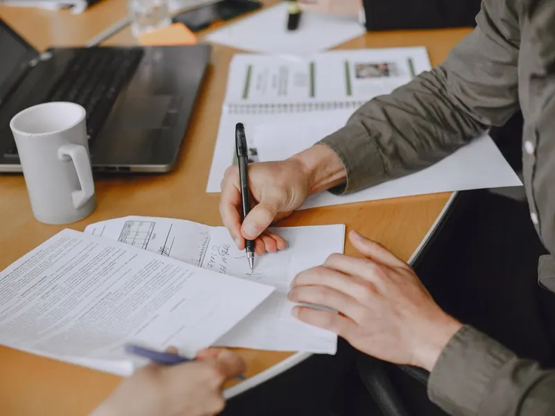 Two people signing business documents at a desk